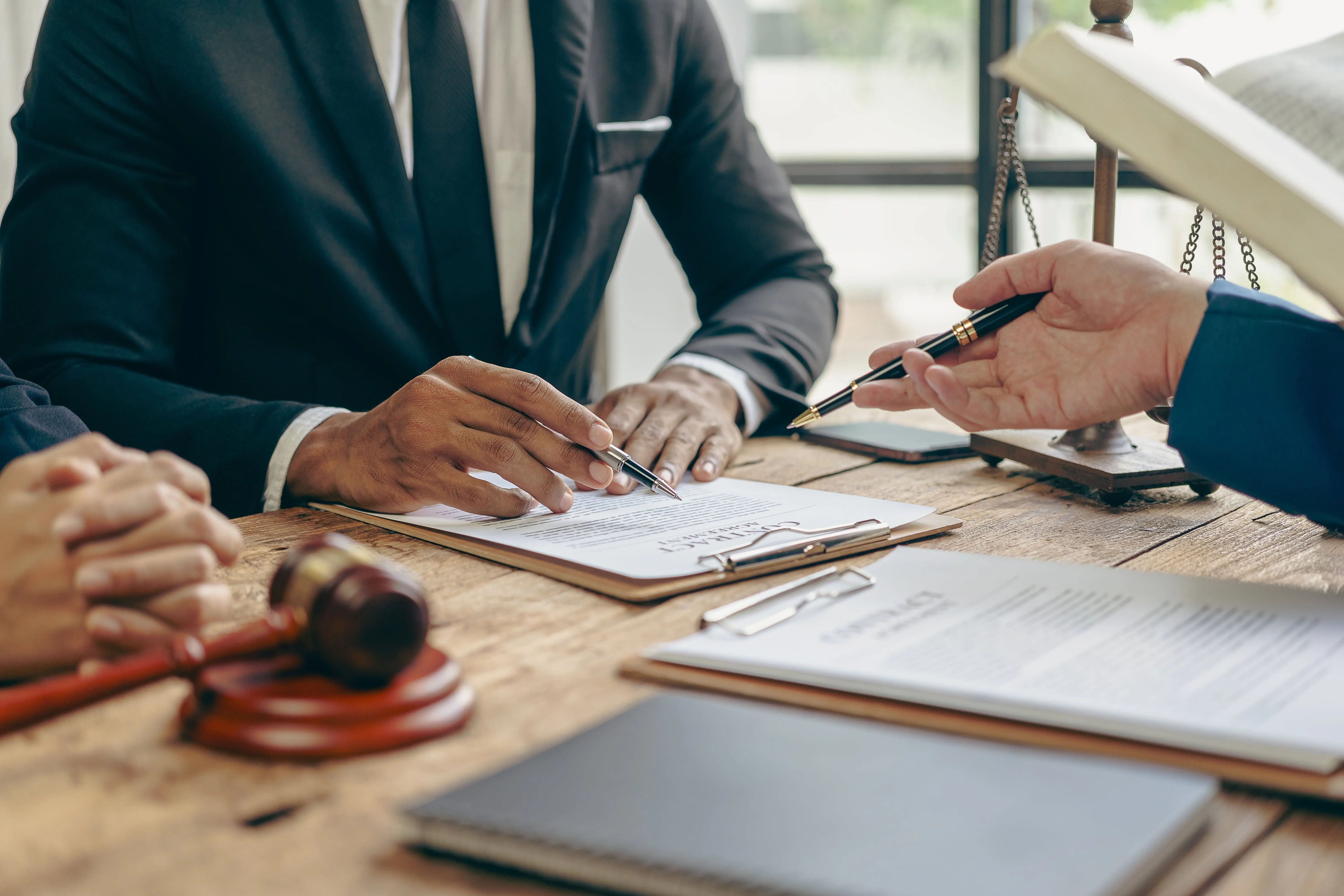personal injury lawyers in kansas city discussing a case, all you can see if their hands and a torso with binders and notebooks on a table